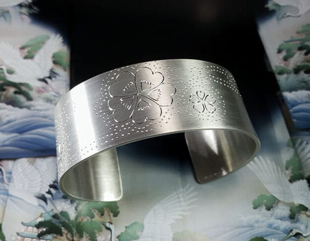Silver cuff bracelet 'Japonais' hand engraved with clover at the brook. Oogst goldsmiths Amsterdam.