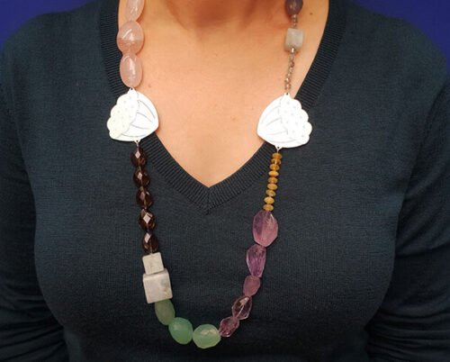 Collier 'Kamon' met zilveren lotus motieven met handgravure en een colourblock edelstenen mix van beryl, amethist, rozenkwarts, aquamarijn, rookkwarts, agaat en chalcedoon. Uit het goudsmid atelier van Oogst.