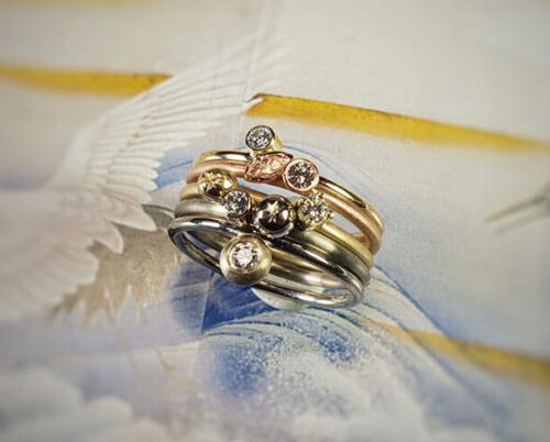 Verlovingsring 'Verzameling' geelgouden ring met eigen diamant, witgouden ring met van eigen goud vervaardigde 'sinaasappel' en eigen diamant, van eigen goud vervaardigde ring met sinaasappel en eigen diamant, roodgouden ring met blaadje en eigen diamant, witgouden ring met eigen diamant. Engagement ring ‘Collection’ yellow golden ring with heirloom diamond, white golden ring with ‘orange’ made of heirloom gold with heirloom diamond, ring made of heirloom gold with orange and heirloom diamond, rose golden ring with leaf and heirloom diamond, white golden ring with heirloom diamond. Oogst goudsmeden Amsterdam.