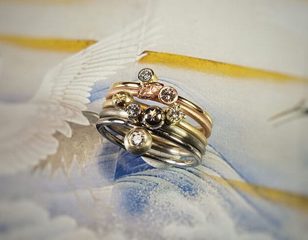 Verlovingsring 'Verzameling' geelgouden ring met eigen diamant, witgouden ring met van eigen goud vervaardigde 'sinaasappel' en eigen diamant, van eigen goud vervaardigde ring met sinaasappel en eigen diamant, roodgouden ring met blaadje en eigen diamant, witgouden ring met eigen diamant. Engagement ring ‘Collection’ yellow golden ring with heirloom diamond, white golden ring with ‘orange’ made of heirloom gold with heirloom diamond, ring made of heirloom gold with orange and heirloom diamond, rose golden ring with leaf and heirloom diamond, white golden ring with heirloom diamond. Oogst goudsmeden Amsterdam.