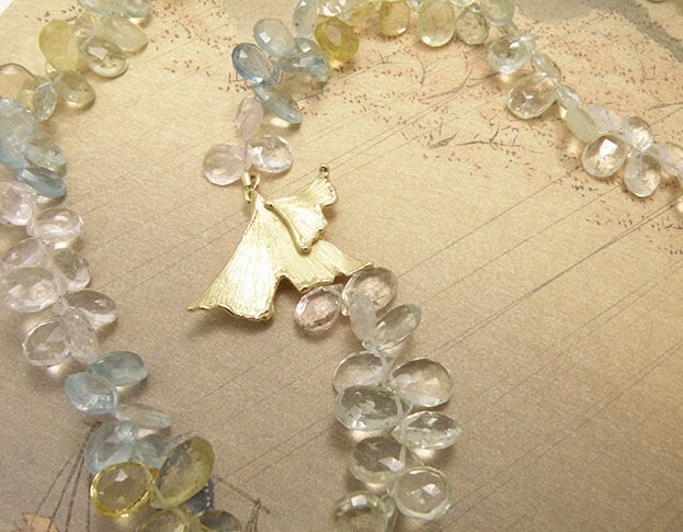 Beryl collier met geelgouden ginkgo biloba blad sluiting. Beryl necklace witch yellow golden ginkgo leaf clasp. Uit het Oogst atelier Amsterdam.
