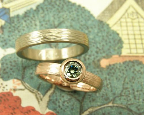 Trouwringen 'Boleet' en ‘Ritme’. Roodgouden ring met hamerslag en paraiba green diamant. Witgouden ring met hamerslag. Wedding rings 'Boletus' & 'Rhythm'. Rose golden ring with hammering and paraiba green diamond. White golden ring with hammering. Oogst goudsmeden Amsterdam.