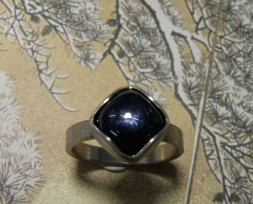 Verlovingsring 'Linnen'. Witgouden ring met linnenstructuur en een antiek geslepen saffier. Engagement ring 'Linnen'. White golden ring with linnen structure and an antique cut sapphire. Uit het Oogst atelier Amsterdam.
