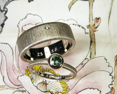 Trouwringen Eenvoud witgouden ring met groene diamant en witgouden ring met fluweel finish. Wedding rings Simplicity white gold ring with a green diamond and white gold textured ring with a Velvet finish Huwelijksringen. edelsmid. Goudsmid Amsterdam. Oogst
