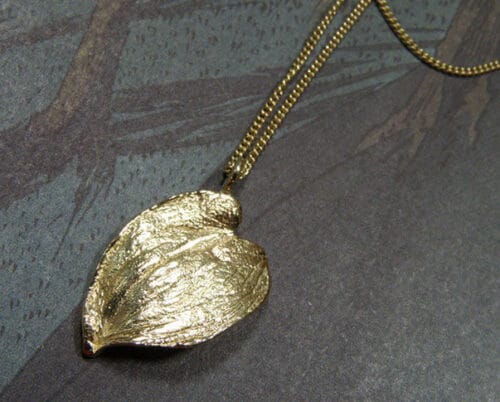 'Boomgaard' collier met geelgouden hartvormig blad bungelend aan een verfijnd gourmet schakelcollier. 'Orchard' necklace with yellow golden hart shaped leaf. Oogst Amsterdam.