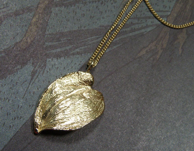 'Boomgaard' collier met geelgouden hartvormig blad bungelend aan een verfijnd gourmet schakelcollier. 'Orchard' necklace with yellow golden hart shaped leaf. Oogst Amsterdam.