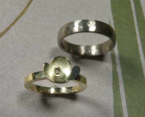 Trouwringen 'Ritme'. Geelgouden ring met kussen hamerslag en bloem met witgouden blaadje en bruine diamant. Witgouden ring met kussen hamerslag. Wedding rings 'Rhythm'. Yellow golden ring with hamering and flower with white golden petals and brown diamond. Yellow golden ring with hammering. Oogst goudsmeden Amsterdam.