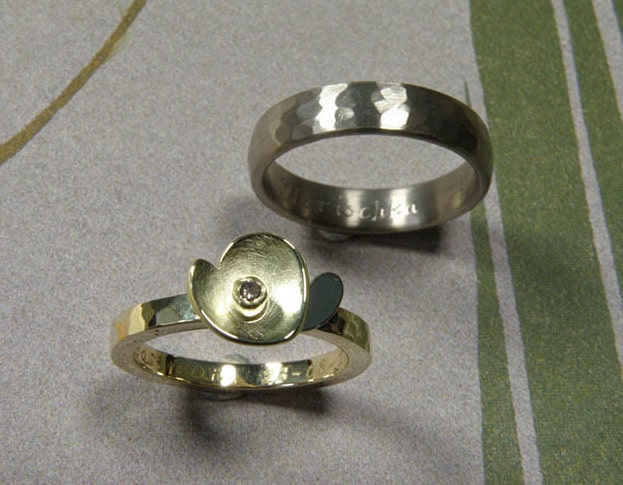Trouwringen 'Ritme'. Geelgouden ring met kussen hamerslag en bloem met witgouden blaadje en bruine diamant. Witgouden ring met kussen hamerslag. Wedding rings 'Rhythm'. Yellow golden ring with hamering and flower with white golden petals and brown diamond. Yellow golden ring with hammering. Oogst goudsmeden Amsterdam.