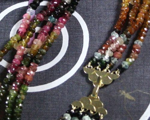 Collier van 4 rijen toermalijn en geelgouden Japanse golf sluiting met hamerslag textuur. Necklace with 4 rows of tourmaline and yellow golden hammered Japanese wave clasp. Uit het Oogst atelier Amsterdam.