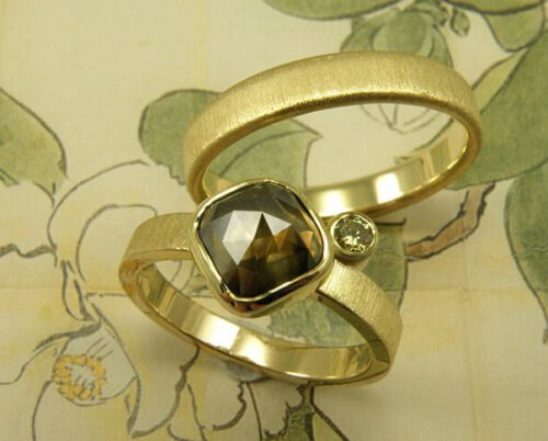 Trouwringen 'fluweel'. Geelgouden ring met een diamant en een olijf diamant. Geelgouden ring met streepjes afwerking. Wedding rings 'Velvet'. Yellow golden ring with a diamond and an olive green diamond. Yellow golden ring with stripey finish. Oogst goudsmeden Amsterdam.