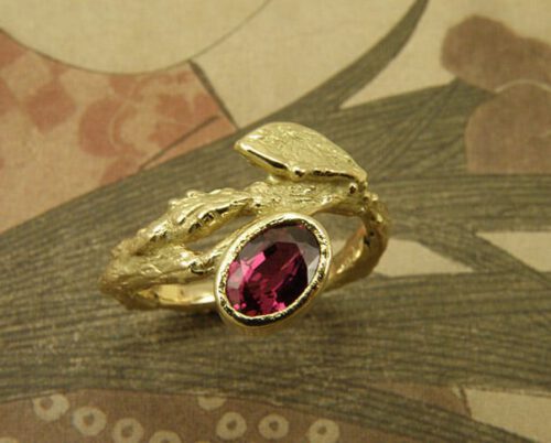 Verlovingsring 'Boomgaard'. Geelgouden takje met blaadje en een ovale robijn. Engagement ring 'Orchard'. Yellow golden twig with leaf and oval ruby. Uit het Oogst atelier Amsterdam.
