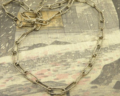 Collier 'Boomgaard' geschakelde herenketting met takjesstructuur van eigen witgoud vervaardigd met een diepblauwe tanzaniet. Necklace ‘Orchard’ mens necklace with twig structure made of heirloom white gold and deep blue tanzanite. Oogst goudsmeden Amsterdam.