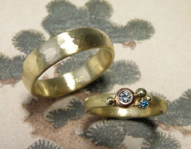 Trouwringen 'Ritme'. Ovale ring met hamerslag en bolletjes met blauwe diamanten vervaardigd van oud goud. Ovale ring met hamerslag vervaardigd van oud goud. Wedding rings 'Rhythm'. Oval ring with hammering, spheres and blue diamond, made from heirloom gold. Oval ring with hammering, made from heirloom gold. Oogst goudsmeden Amsterdam.