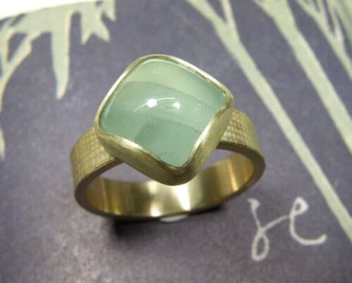 Verlovingsring 'Linnen'. Geelgouden linnenstructuur met kussen geslepen aquamarijn. Engagement ring 'Linnen'. Yellow golden ring with linnen structure and aquamarine. Oogst goudsmeden Amsterdam.