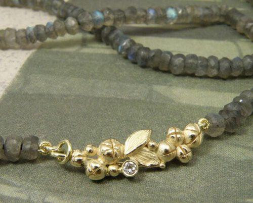 Collier 'Bessen' besjes en bladeren sluiting vervaardigd uit oud goud met eigen diamant aan fonkelende labradoriet. Necklace ‘Berries’ berries and leafs clasp made of heirloom gold with heirloom diamond and sparkling labradorite. Uit het Oogst atelier Amsterdam.