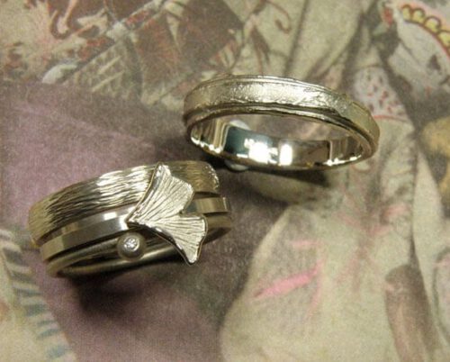 Partnerringen 'Verzameling' en 'Erosie'. Witgouden aanschuifringen met spitse hamerslag, ginkgo blaadje, bol en diamant. Witgouden ring met gelaagde structuur. Wedding rings 'Collection' & 'Erosion'. White golden stack rings with hammering, ginkgo leaf, sphere and diamond. White golden ring with layered structure. Oogst Amsterdam.