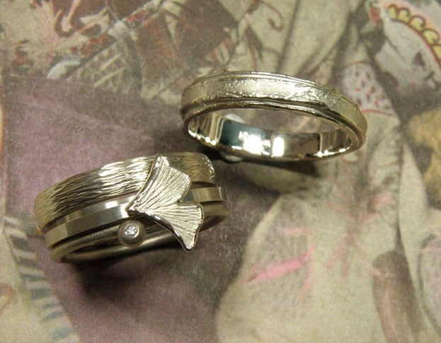 Partnerringen 'Verzameling' en 'Erosie'. Witgouden aanschuifringen met spitse hamerslag, ginkgo blaadje, bol en diamant. Witgouden ring met gelaagde structuur. Wedding rings 'Collection' & 'Erosion'. White golden stack rings with hammering, ginkgo leaf, sphere and diamond. White golden ring with layered structure. Oogst Amsterdam.