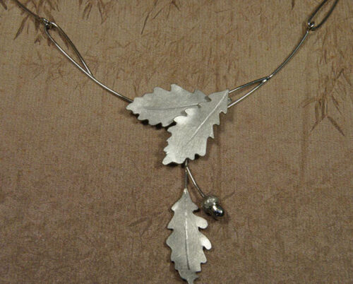 Persoonlijk gedenksieraad. Witgouden collier 'Eik' van elegante schakels, eikenblaadjes en een eikendopje. Handgemaakt in het Oogst goudsmid atelier in Amsterdam.