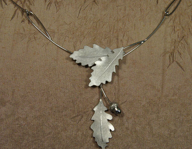 Persoonlijk gedenksieraad. Witgouden collier 'Eik' van elegante schakels, eikenblaadjes en een eikendopje. Handgemaakt in het Oogst goudsmid atelier in Amsterdam.