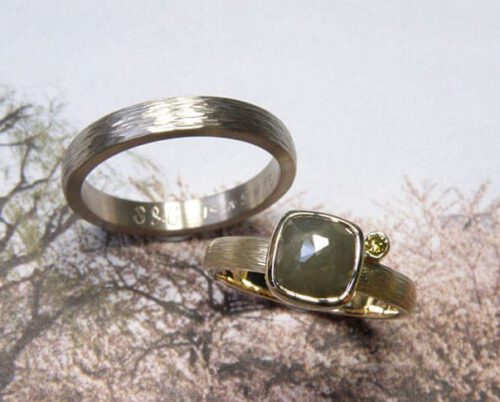 Trouwringen Ritme. Van eigen oud goud vervaardigde ring met hamerslag en een olijf en groene diamant. Witgouden ring met hamerslag. Wedding rings 'Rhythm'with hammering. Made from own heirloom gold and a green and olive diamond for her. White gold for him. Oogst ontwerp & creatie