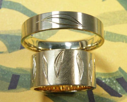 Handgegraveerde trouwringen 'Lineair'. Geelgouden brede ring met rondom bladeren. Geelgouden ring met een blad. Hand engraved wedding rings 'Lineair'. Yellow golden wider ring with leaves all around. Yellow golden ring with leafs. Oogst goudsmeden Amsterdam.