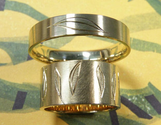 Hand engraved wedding rings 'Lineair'. Yellow golden wider ring with leaves all around. Yellow golden ring with leaf. Oogst goldsmith studio Amsterdam.