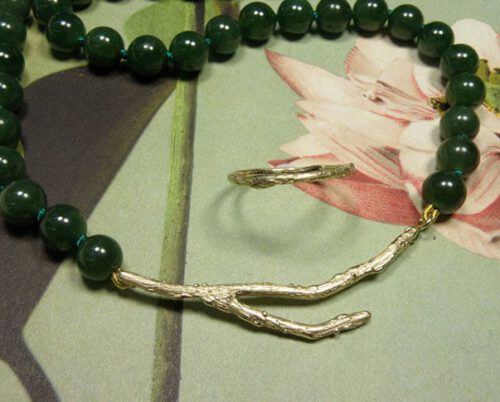 Collier 'Boomgaard' takjes sluiting vervaardigd van eigen trouwringen gecombineerd met ronde jade meegebracht van een reis & ring ‘Boomgaard’ takje vervaardigd van eigen trouwringen. Necklace ‘Orchard’ twig clasp made from heirloom wedding rings combined with round jade brought home from a trip & ring ‘Orchard’ twig made from heirloom wedding rings. Oogst goudsmeden Amsterdam.