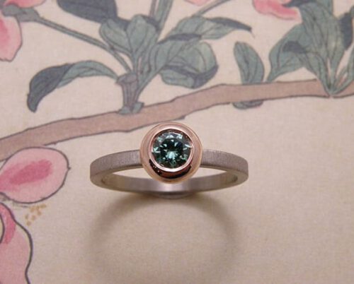 Ring 'boleet' witgouden ring met diamant fancy paraiba groen in een roodgouden boleet zetting met een fluweel afwerking. Ring ‘Boletus’ white golden ring with diamond fancy paraiba green in a rose golden boletus setting with velvet finish. Uit het Oogst atelier Amsterdam.