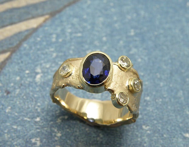 Ring 'Erosie' verlopende ring met structuur vervaardigd van eigen geelgoud met eigen diamanten en saffier uit een dierbare, maar versleten, ring. Ring ‘Erosion’ ring with structure made of heirloom yellow gold, diamonds and sapphire from a beloved, but worn out, ring. Uit het Oogst atelier Amsterdam.