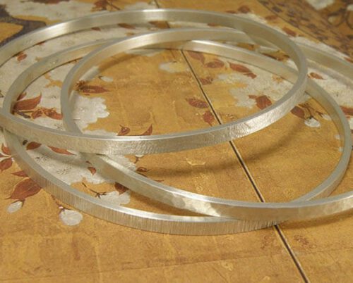 Zilveren rinkelbanden, ieder met een andere structuur. Silver bangles with different structures. Uit het Oogst atelier Amsterdam.