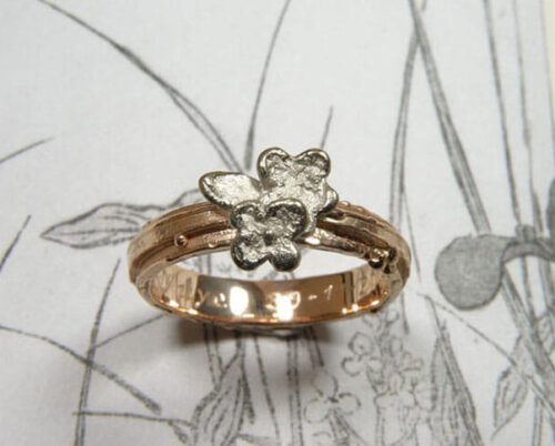 Roodgouden structuur ring met witgouden bloemen. Rose gold textured ring with white gold flowers. Uit het Oogst goudsmid atelier. Made in the Oogst goldsmith studio.