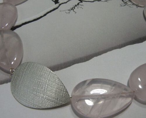 Druppelvorm geslepen rozenkwarts met zilveren sluiting en linnen structuur. Drop shape rose quartz necklace with silver clasp and linnen structure. Oogst Amsterdam.