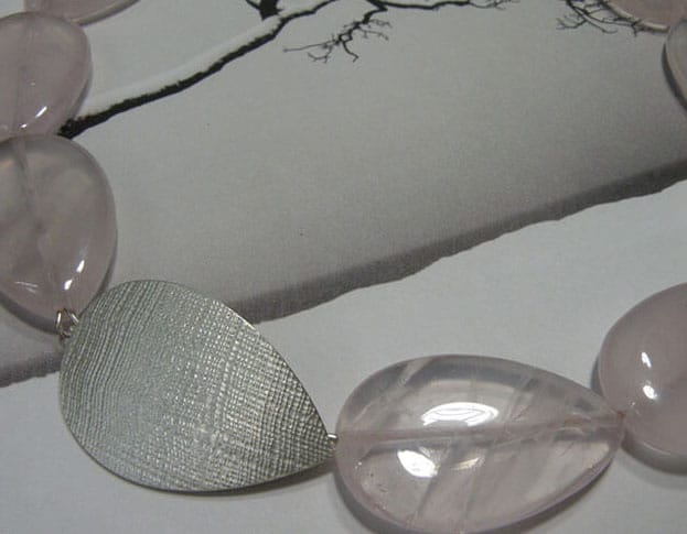 Druppelvorm geslepen rozenkwarts met zilveren sluiting en linnen structuur. Drop shape rose quartz necklace with silver clasp and linnen structure. Oogst Amsterdam.