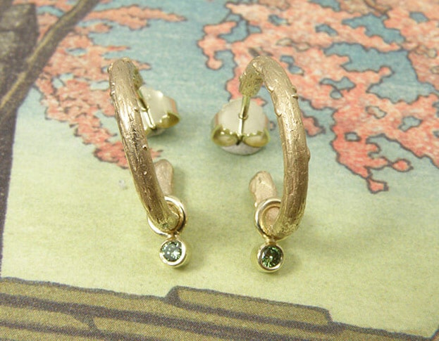 Oorsieraden 'Boomgaard' takjes creolen van eigen goud vervaardigd met 2x 0,05 crt diamant fancy green. Earrings ‘Orchard’ twig earrings made of heirloom gold with 2x 0,05 crt diamond fancy green. Uit het Oogst atelier Amsterdam.