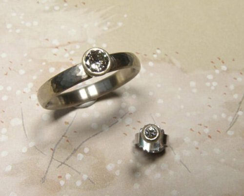 Trouwring'Ritme' witgoud met fijne hamerslag en eigen diamant. Oorsieraad 'Boleet' witgoud met eigen diamant. Wedding ring 'Rhythm' whitegold with hammering and own diamond. Earring 'Boletus' white gold with own diamond. Oogst goldsmith Amsterdam