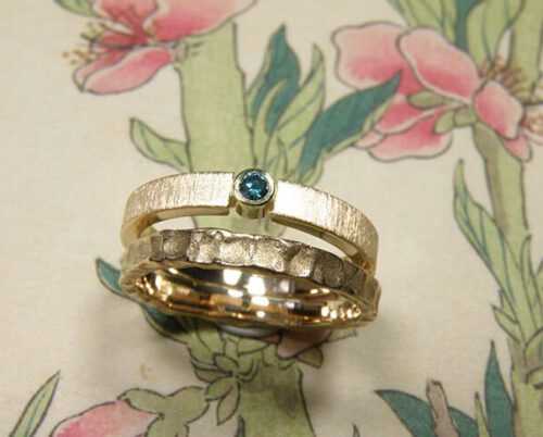 Trouwring Deining en Eenvoud. Aanschuifringen met structuur en ocean blue diamant. Van eigen goud vervaardigd. Wedding rings Swell and Simplicity. Stack rings. made from heirloom gold. With ocean blue diamond. Oogst goldsmith Amsterdam. Edelsmid.
