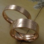 Trouwringen 'Lineair'. Roodgouden ring met handgravure art deco en roodgouden ring met handgravure franse lelie en palmbladeren. Wedding rings 'lineair'. Rose golden ring with art deco hand engraving and rose golden ring with french lillies and palm leafs hand engraving. Oogst goudsmeden Amsterdam.