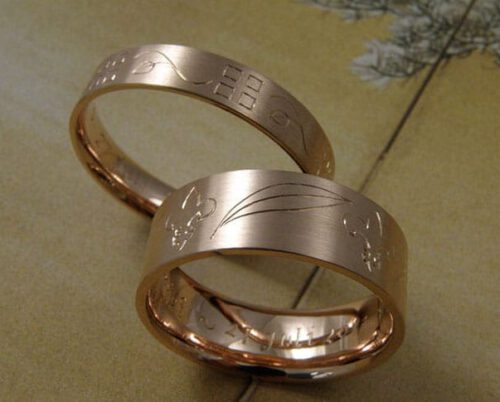 Trouwringen 'Lineair'. Roodgouden ring met handgravure art deco en roodgouden ring met handgravure franse lelie en palmbladeren. Wedding rings 'lineair'. Rose golden ring with art deco hand engraving and rose golden ring with french lillies and palm leafs hand engraving. Oogst goudsmeden Amsterdam.