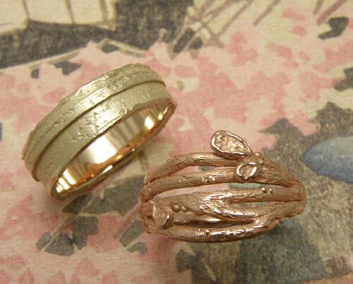 Partnerringen 'Boomgaard' en 'Erosie'. Roodgouden twijgjes ring met blaadjes en geelgouden gelaagde structuur ring. Wedding bands 'Orchard' & 'Erosion'. Rose golden twig ring with leafs and a yellow golden ring layered ring with structure. Oogst goudsmeden Amsterdam.