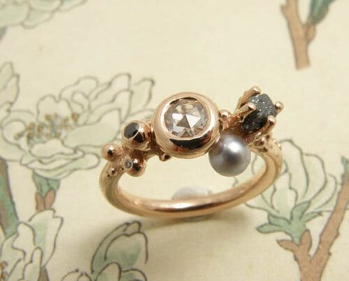 Verlovingsring 'Verzameling' roodgouden ring met bolletjes, diamanten en lichtgrijze parel. Engagement ring ‘Collection’ rose golden ring with spheres, diamonds and light grey pearl. Uit het Oogst atelier Amsterdam.