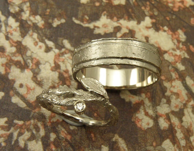 Trouwringen 'Boomgaard' en 'Erosie'. Witgouden ring met takje, blaadje en diamant. Witgouden gelaagde structuur ring. Wedding rings 'Orchard' & 'Erosion'. White golden ring with twig, leaf and diamond. White golden layered ring with structure. Uit het Oogst atelier Amsterdam.