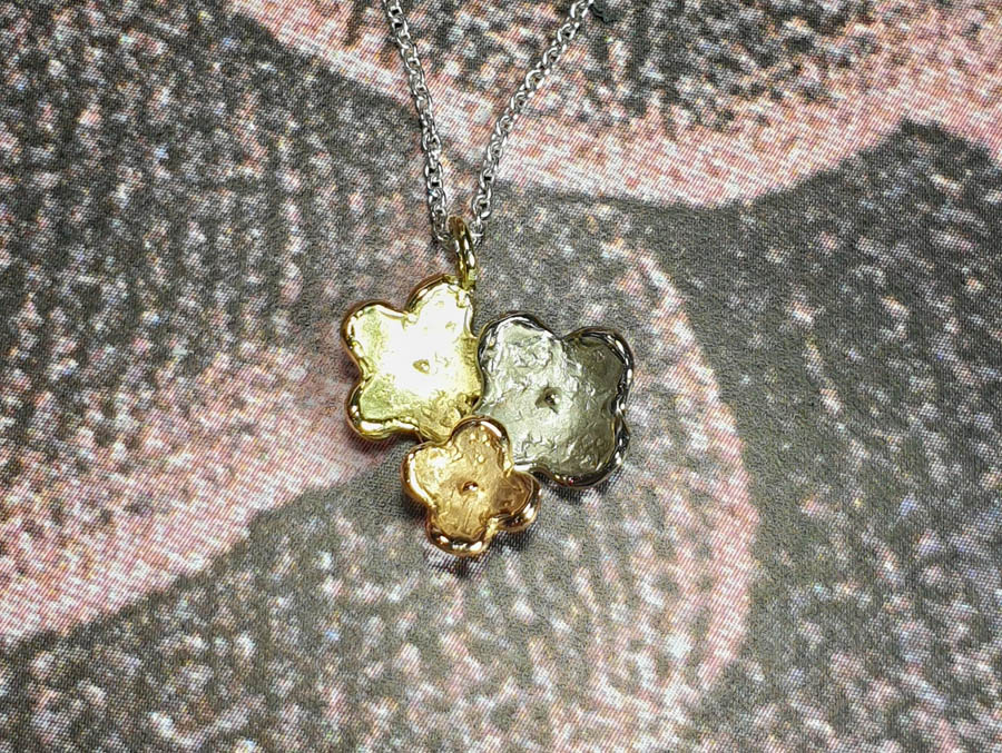 In bloei hanger 3 bloemen in geelgoud, witgoud en roodgoud. Baargoud. Geboortecadeau. Birth present. Gold pendant Flowers in yellow gold, white gold and rose gold. Oogst edelsmid Amsterdam
