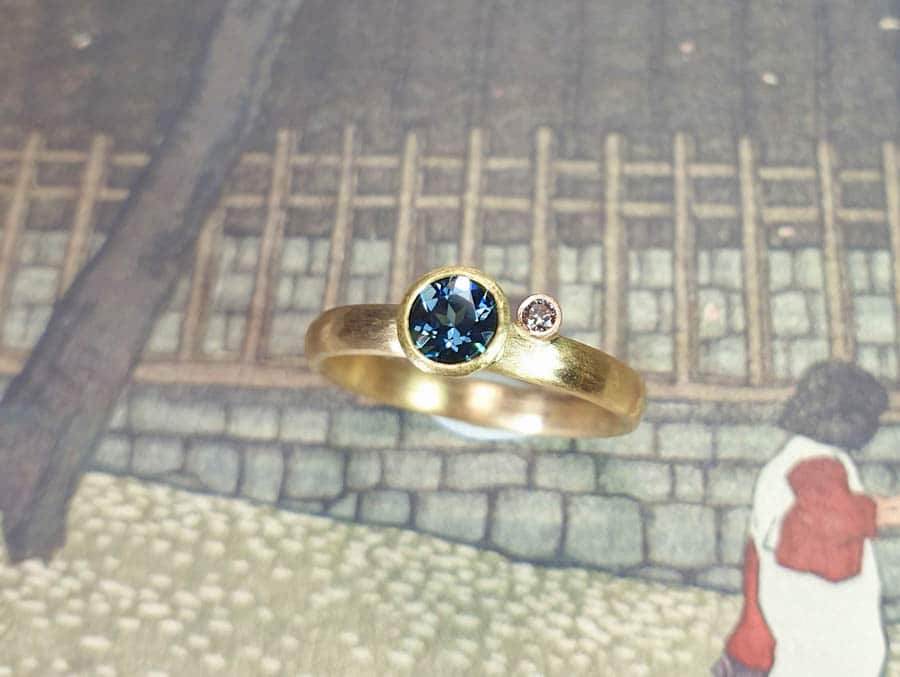 Rosé gold engagement ring with a petrol blue spinel and pinkish brown diamond and hammering. Jewellery design by Oogst in Amsterdam
