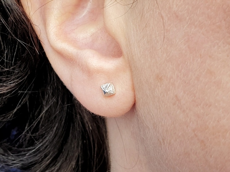 Silver ear studs from the 'Crystals' series. Pyramid shapes. Design by Oogst Goldsmith in Amsterdam. Seen on the earlobe.