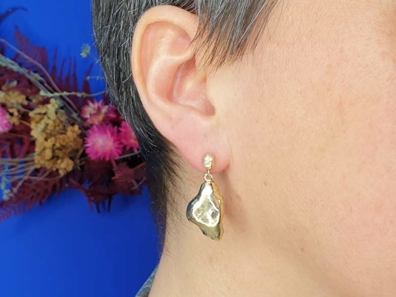 Geelgouden oorsieraden 'Wolken' met een hoekig kristal en steker. Ontwerp van Oogst goudsmid Amsterdam uit de Amorf vs Kristallijn collectie.