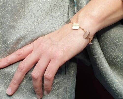 Roodgouden armband 'Vouwen' met witgouden, roségouden en geelgouden bedels. Ontwerp van Oogst goudsmid Amsterdam
