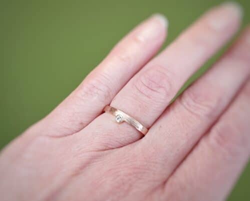Ring Ritme met spitse hamerslag. Roodgouden verfijnde ring met diamant, speels aan de zijkant gezet. Verlovingsring. Trouwring. Oogst goudsmid in Amsterdam.