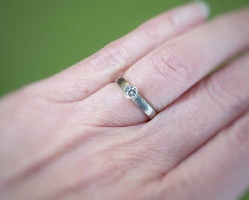 Trouwring Ritme witgouden ring met hamerslag en een 0,20 ct briljant geslepen diamant in een conische zetting. Ontwerp van edelsmid Oogst