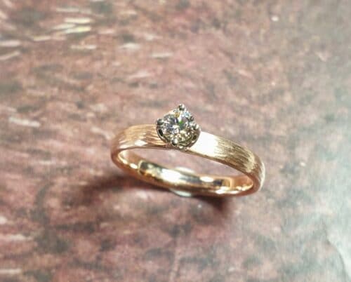 Roodgouden verlovingsring 'Ritme' met spitse hamerslag en briljant geslepen diamant in witgouden tulp chaton.