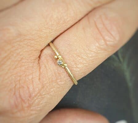 Geelgouden ring 'Besjes' met een diamantje om de vinger. Sieraadontwerp Oogst in Amsterdam.